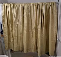 Front view of gathered gold drapery panels hung to show full length and fabric texture