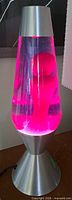Full view of lava lamp lit, showing silver base and cap