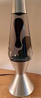 Front view of lava lamp showing silver base, cap, clear globe with black wax inside