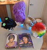 Group shot showing six wigs on stands plus two packaged wigs