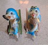 Two resin dolphin figurines on beach chairs