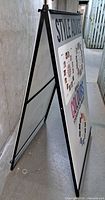 Side view of assembled black metal A-frame sign with printed panel inserted