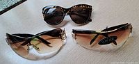 Three pairs sunglasses on surface showing styles and lenses