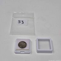 Overall lot: coin in open display case with lid beside and plastic bag above