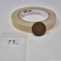 Coin in plastic bag next to tape roll showing size