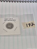 Obverse of 1944 Mercury dime in labelled flip beside lot number tag