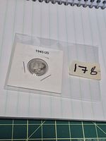 Coin in labelled flip next to lot tag