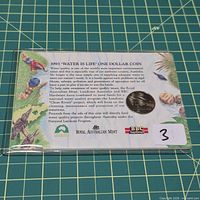 Front of presentation card showing artwork, coin inset, logos