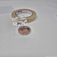 .999 copper round in capsule inside plastic bag with masking tape roll for scale