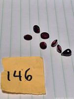Group view of seven dark-red faceted stones on lined paper