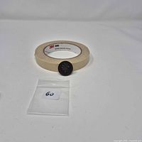 Token in plastic sleeve beside tape roll for scale