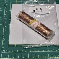 Full view of sealed penny roll in plastic bag with lot label