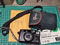 Camera front with lens markings, Lowepro case, manual visible