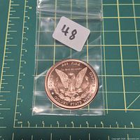 Copper round in plastic bag on measuring mat, eagle side visible