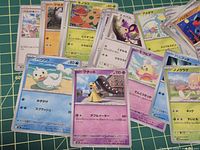 Spread of assorted Japanese Pokémon cards on cutting mat