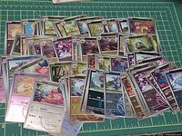 Spread of Simplified Chinese Pokémon cards on cutting mat showing variety and holographic finishes