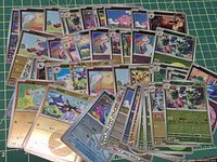 Pile of assorted Simplified Chinese Pokémon cards, mix of holo and regular, cutting mat background