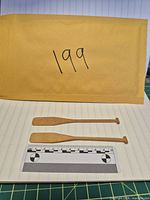 Both miniature wooden paddles laid flat with envelope showing lot number