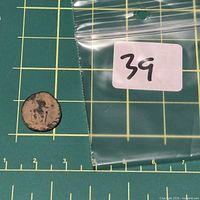 Overall view of coin beside resealable bag marked 39 on measurement grid