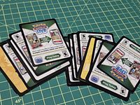 Two stacks of Pokémon TCG Live code cards spread out on cutting mat