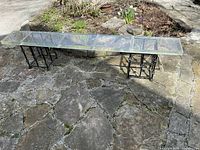 Full view of long clear acrylic slab resting on two metal bases outdoors