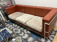 Full front view of three-seat sofa showing frame, leather panels and beige seat covers