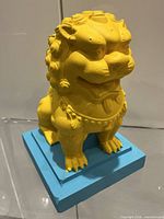 Front view of yellow lion on blue base