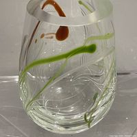 Front view of clear crystal vase showing etched white lines and green, amber ribbons