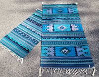 Two Zapotec rugs laid out side by side showing full patterns and fringe