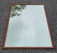 Full view of rectangular wood-framed mirror on ground