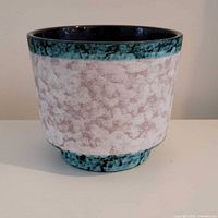 Side view showing speckled matte body, teal rim and foot