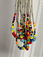 Close-up of clustered necklace strands showing multi-coloured seed beads and silver-tone tubes