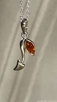 Close-up of pendant detailing curved silver form and marquise amber