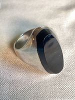 Side angle showing chunky silver band and oval black onyx stone
