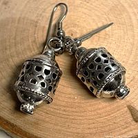 Pair of sterling silver lantern-style dangle earrings on wood background