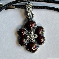 Close-up of sterling silver flower pendant showing marcasite stones, red petals and bail detail