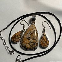 Pendant, earrings and leather cord arranged together front view