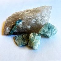 Quartz host rock with visible aquamarine crystal along edge plus three loose aquamarine pieces