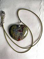 Full view of heart pendant on green cord