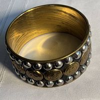 Full view of bracelet showing decorative studs and coin motifs