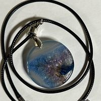 Pendant necklace coiled to show round agate slice and cord