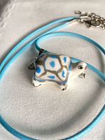 Full view of glass turtle pendant on blue cord with clasp