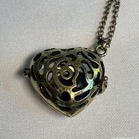 Closed heart locket showing gold tone filigree design