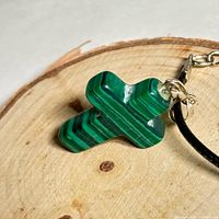 Close-up of malachite cross showing banded green pattern and bail