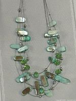 Full view of necklace hanging to show strands, shell pieces, beads, spacers
