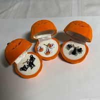 Three open pumpkin boxes showing ghost, black cat and spider jewelry sets