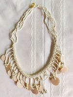 Full view of off-white seed bead choker with shell disc fringe