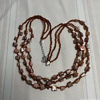 Full view of triple strand necklace laid flat