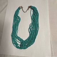 Full view of necklace front showing nine turquoise bead strands and extender chain