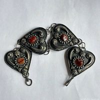 bracelet partially unhooked showing four heart panels and stones